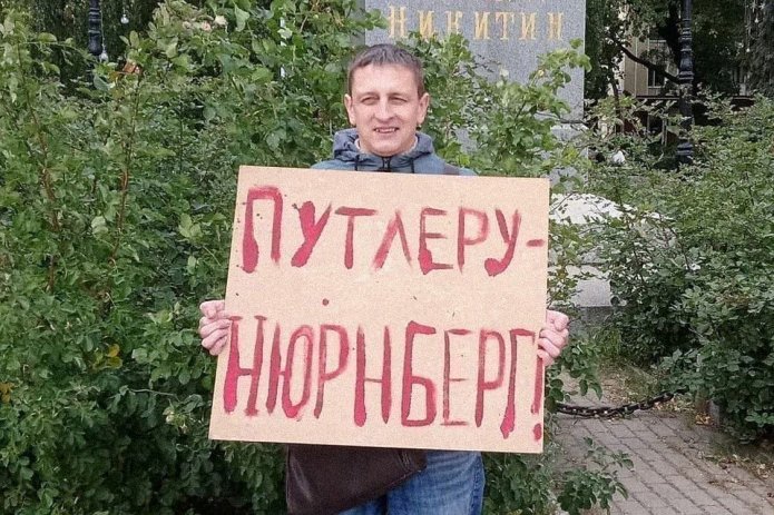 <em>Григорий Северин в одиночном пикете. За этот же плакат в январе 2021 года его <a href="https://bpxuiuka---mekodxpr-bsccljbcrq-ez.a.run.app/express-news/2021/01/20/voronezhca-arestovali-iz-za-odinochnogo-piketa-v-podderzhku-navalnogo"><u>арестовали</u></a> на пять суток (ч. 8 ст. 20.2 КоАП РФ) / Фото: Свободные Люди Воронежа</em>